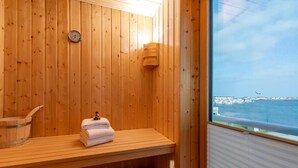 Un sauna de madera con un banco, una toalla y un termómetro en la pared.