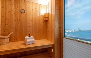 Relax in a serene sauna with a bench and table, overlooking a stunning coastal view.