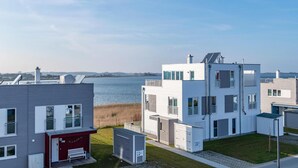 Una zona residencial moderna con vistas a un cuerpo de agua, con arquitectura contemporánea y cielo despejado.
