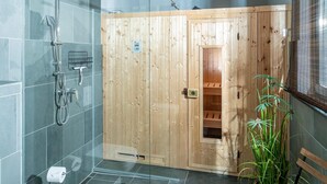 Un sauna avec des murs en bois, une porte en verre et un banc.