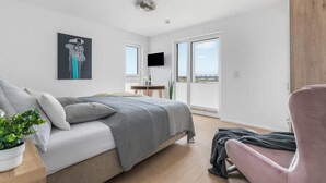 Une chambre moderne avec un lit, une chaise, une télévision et un balcon offrant une vue agréable.