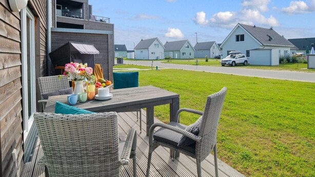Un patio con mobiliario de mimbre y una mesa adornada con flores y vajilla.