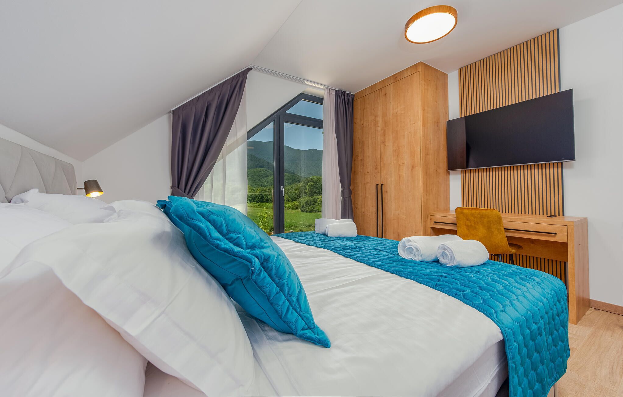 Een moderne hotelkamer met een groot bed, een bureau en een televisie.