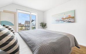 Une chambre avec un grand lit, une vue sur la côte et un tableau représentant un phare.