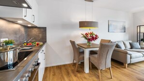 A modern kitchen with a dining area, a sofa, and a table with a vase of flowers. - Beautiful apartment in Olpenitz (Olpenitz)