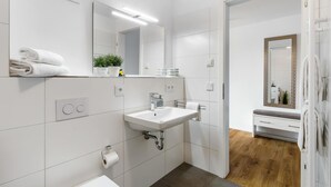 A modern bathroom with a white sink, mirror, and towel rack. - Beautiful apartment in Olpenitz (Olpenitz)