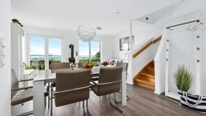 A modern interior with a dining area, a fireplace, a staircase, and a view of the outdoors.