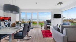 Ein modernes Wohnzimmer mit großem Fernseher, einer Couch und einem Essbereich mit Tisch und Stühlen.