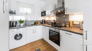 A modern kitchen with white cabinets, stainless steel appliances, and a built-in oven.