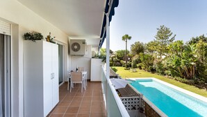 Un balcon avec une piscine, une table et des chaises, ainsi qu’un jardin agrémenté de diverses plantes et arbres.