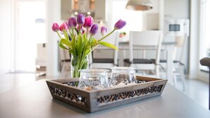 Un plateau avec des tulipes et des verres est posé sur une table dans une pièce lumineuse, avec une cuisine moderne en arrière-plan.