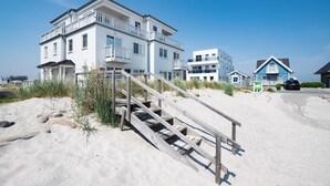 Une propriété située en bord de mer, avec un escalier en bois menant à un bâtiment blanc doté de plusieurs balcons.