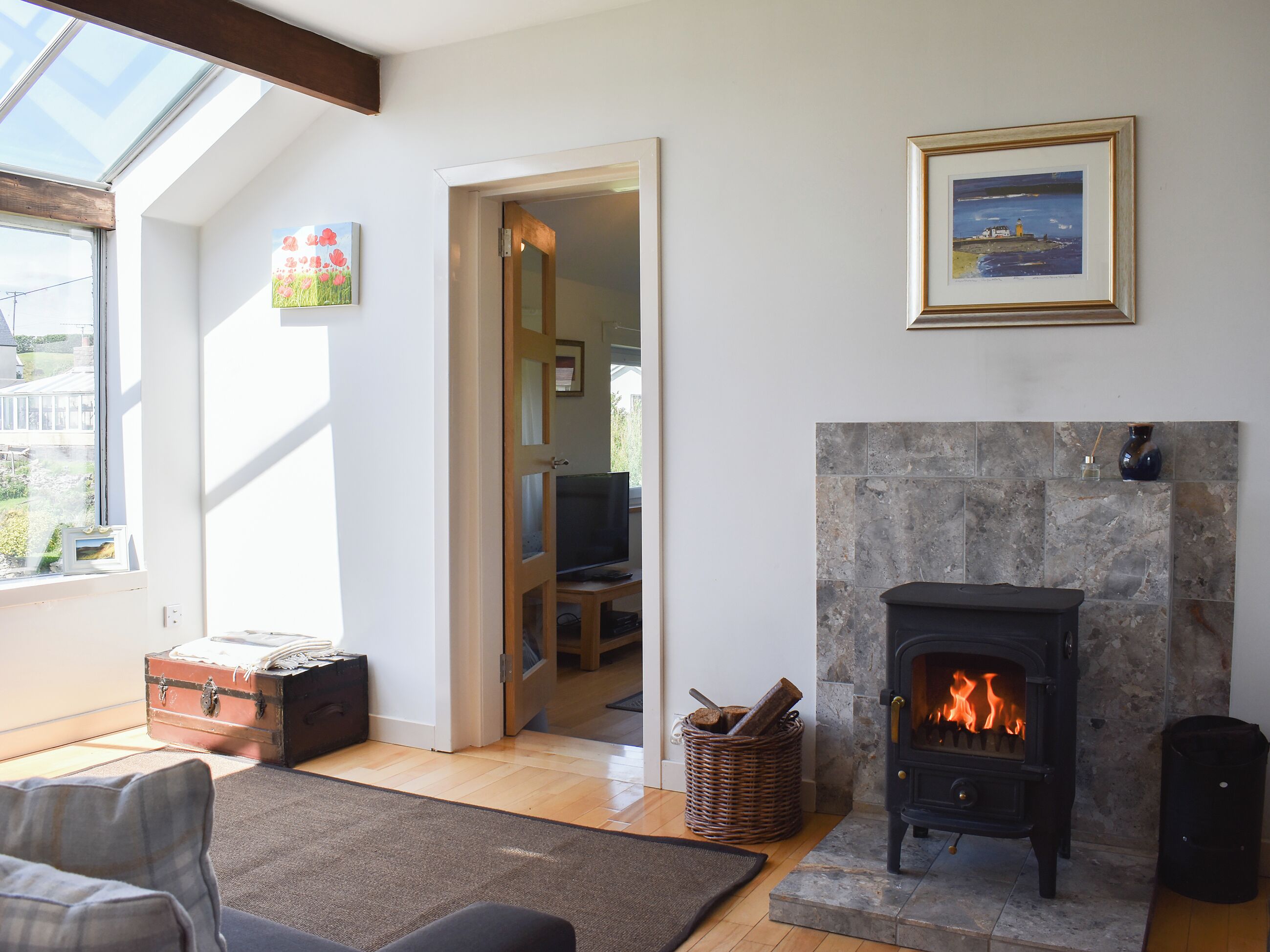 A living room with a fireplace, a television, and a view through a window.