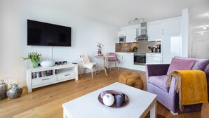 A modern living room with a flat-screen TV, a coffee table, and a sofa.