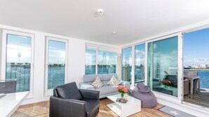 A modern living room with a sofa, coffee table, and a view of the water. - Lovely ship in Olpenitz with sauna (Olpenitz)