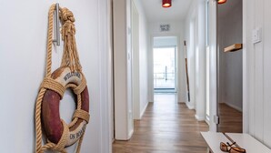 A hallway with a rope life preserver hanging on the wall, a wooden floor, and a view of a balcony in the distance. - Lovely ship in Olpenitz with sauna (Olpenitz)