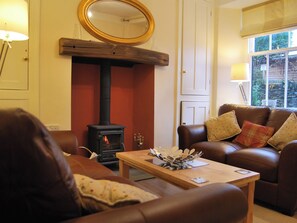 A living room with a fireplace, leather sofa, wooden coffee table, and a mirror on the wall. - A charming, contemporary Lakeland cottage in the very heart of Ambleside. (Ambleside)