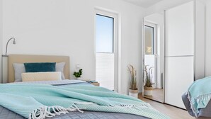 A modern bedroom with a bed, bedside table, and a potted plant. - Nice apartment in Olpenitz with sauna (Olpenitz)