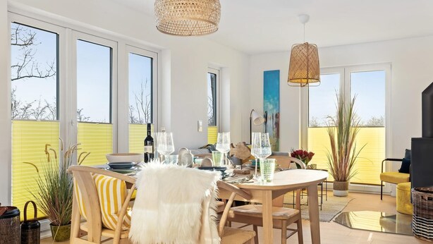 A modern dining area with a round table, chairs, and a large window. - Nice apartment in Olpenitz with sauna (Olpenitz)