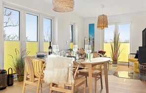 A modern dining area with a round table, chairs, and a large window. - Nice apartment in Olpenitz with sauna (Olpenitz)