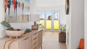 A bright kitchen with a dining area, a large painting, and a view through the glass door. - Nice apartment in Olpenitz with sauna (Olpenitz)