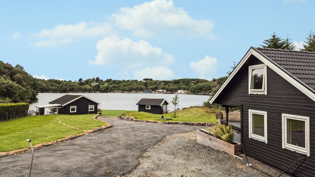 A residential area with a house, a small building, and a body of water in the background.