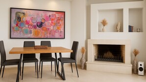 Un coin repas avec une table et des chaises en bois, une cheminée et un grand tableau abstrait accroché au mur.