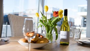 A dining table with a plate of pastries, a glass of water, and a bottle of wine. There are tulips in a vase and a chair in the background. - Cozy home in Olpenitz with sauna (Olpenitz)