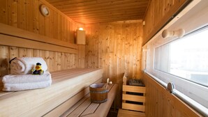 A wooden sauna room with benches, a towel, a rubber duck, and a bucket. - Cozy home in Olpenitz with sauna (Olpenitz)