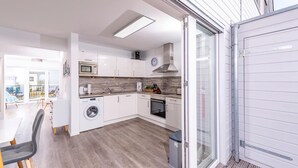 Una cocina moderna con armarios blancos, microondas, lavadora y horno.