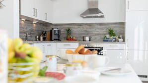 Una cocina moderna con armarios blancos, una campana extractora de acero inoxidable y un salpicadero de madera.