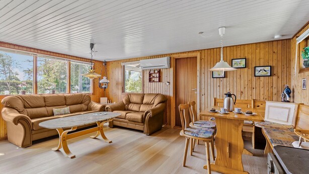 Une pièce chaleureuse avec un décor intérieur en bois, un canapé, une table basse, une table à manger avec des chaises et une cheminée.