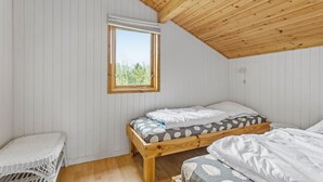 Une petite cabane d’une seule pièce, avec un plafond en pente et une fenêtre donnant sur la verdure.