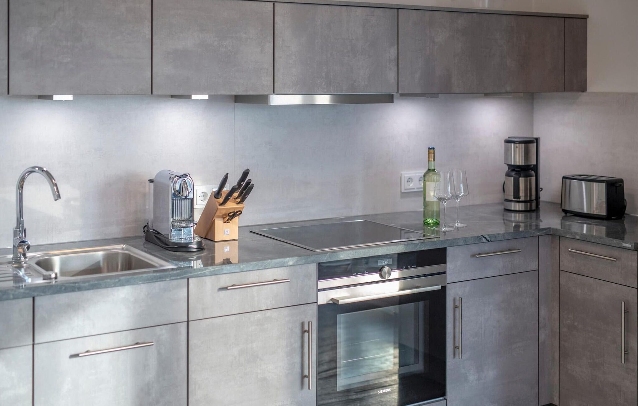 A modern kitchen with stainless steel appliances, a built-in oven, and a coffee maker.