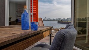 Una mesa de madera con dos botellas de vidrio azul y un vaso transparente. Una silla gris está colocada frente a la mesa.