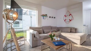 Una sala de estar moderna con un sofá modular, una mesa de centro de madera y un telescopio sobre un trípode.