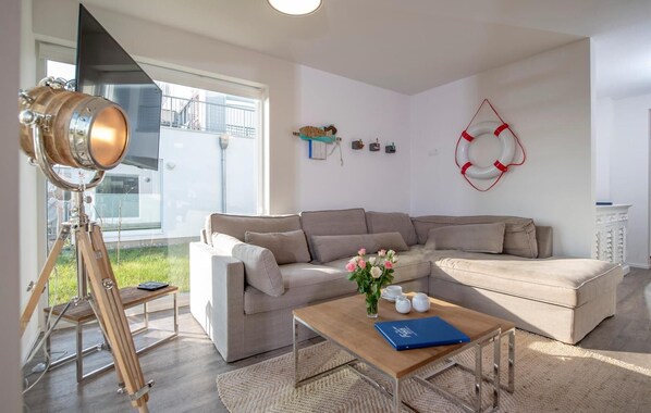 A modern living room with a sectional sofa, a wooden coffee table, and a telescope on a tripod. - Nice apartment in Olpenitz with sauna (Olpenitz)