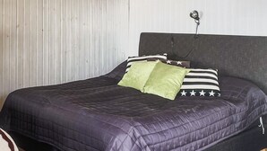 Ein ordentlich bezogenes Bett mit einer dunklen Decke, zwei Kissen mit Sternenmuster und einem grünen Kissen.