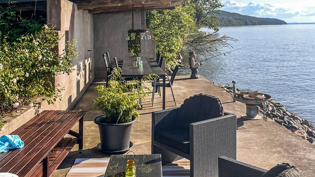 Eine Terrasse im Freien mit Tisch, Stühlen und einem Feuerkorb am See.