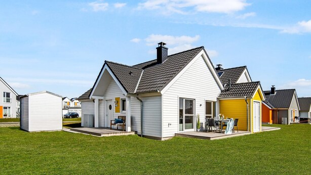 A single-story house with a front porch, a small attached garage, and a well-maintained lawn. - 2 bedroom beach front home in Olpenitz (Olpenitz)
