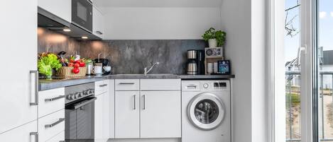 Una cocina moderna con una lavadora Bosch, una cafetera y un lavabo.