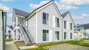 Een woonhuis met twee verdiepingen, voorzien van een trap naar de bovenverdieping, een voortuin en een kleine veranda.