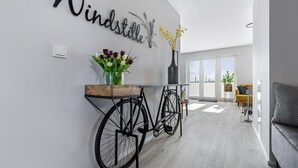 Una sala de estar moderna con una pared blanca, una mesita de madera con flores, una bicicleta negra y un sofá amarillo.