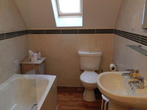 Un bagno con finestra sul tetto, un water, un lavandino e una vasca da bagno.