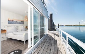 A modern room with a bed, a large window, and a view of the water. - Awesome ship in Olpenitz with sauna (Olpenitz)