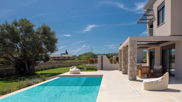 Una casa moderna con piscina, mobiliario exterior y fachada de piedra.