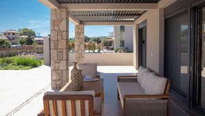 Un espacio de estar al aire libre cubierto, con pilares de piedra, un sofá y una mesa.