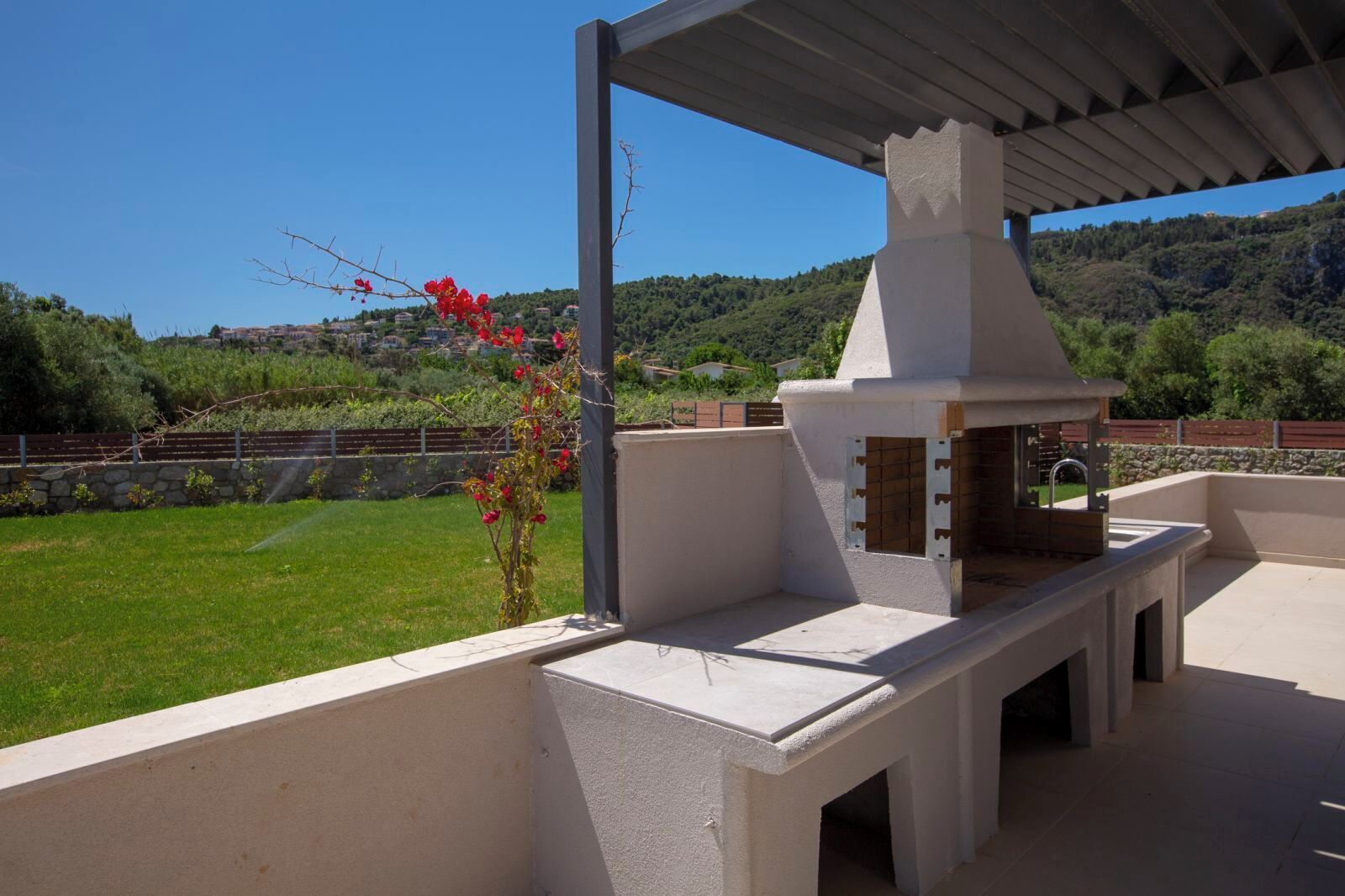 An outdoor patio with a built-in grill and a pergola structure.