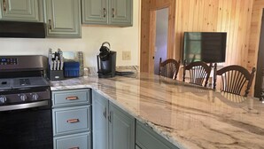 A kitchen with green cabinets, a black stove, and a marble countertop. - Right on the Tuscobia Trail Cozy 2-bedroom cabin in  Winter with WiFi,  AC  (Winter)