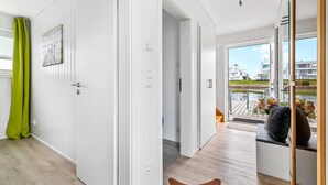 Ein modernes Interieur mit Holzboden, weißen Wänden und Blick auf eine Wohngegend durch eine Glastür.